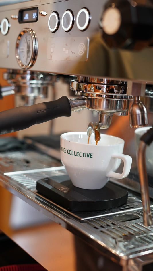 Espresso machine with a white mug labeled 'Collective' on a blurred background